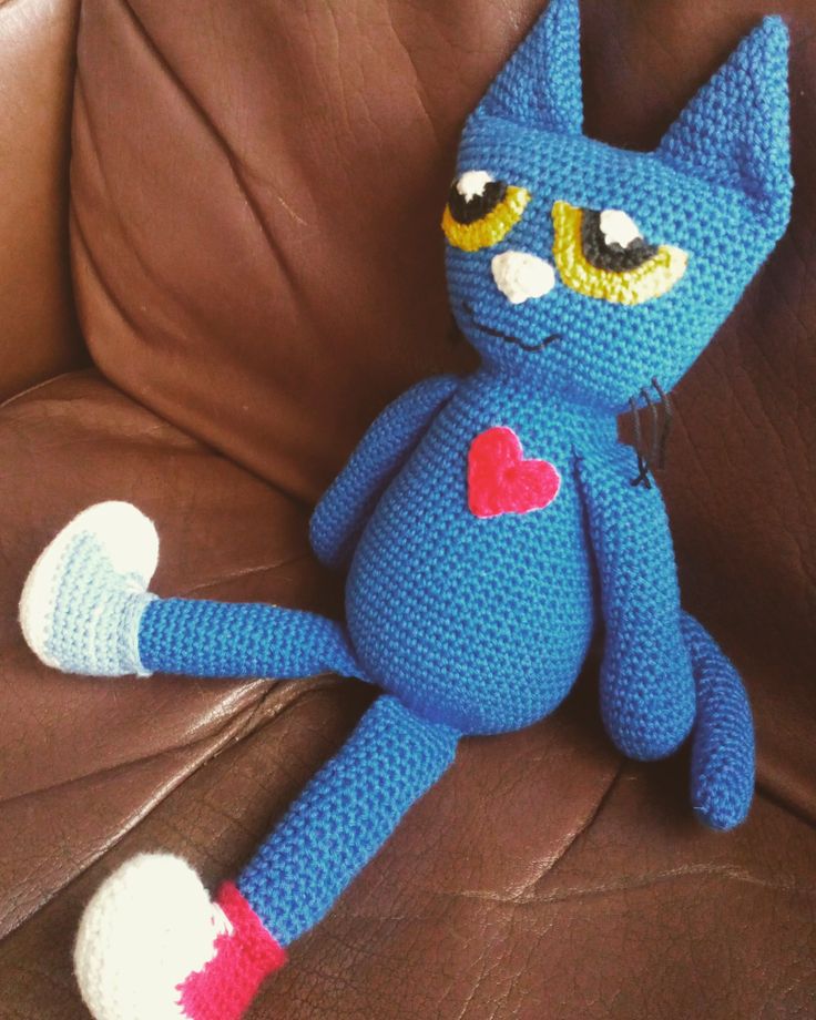 a crocheted blue cat sitting on top of a couch