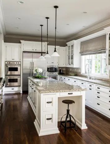 a large kitchen with white cabinets and wood floors