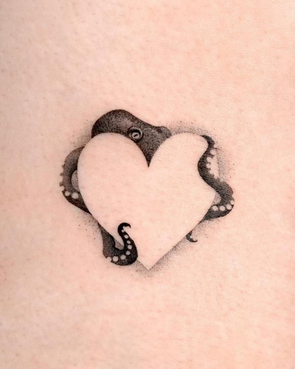 a heart shaped tattoo on the back of a woman's stomach with an octopus in it