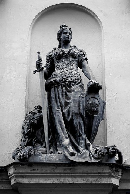 a black and white photo of a statue on the side of a building with a lion