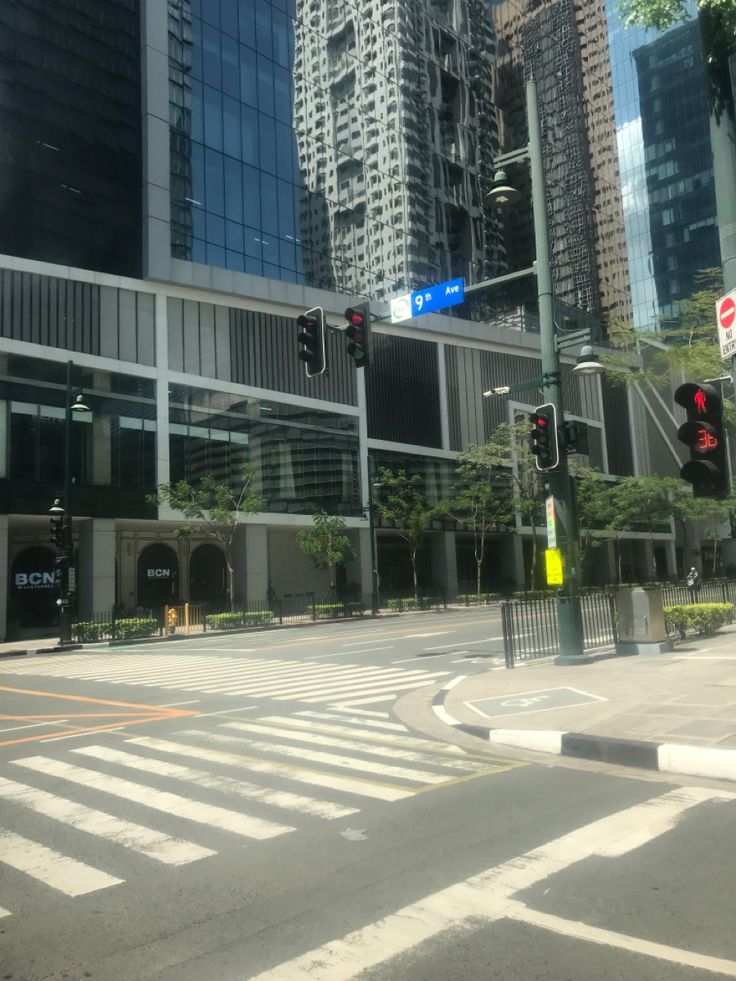 an empty intersection in the middle of a city with tall buildings and traffic lights on either side