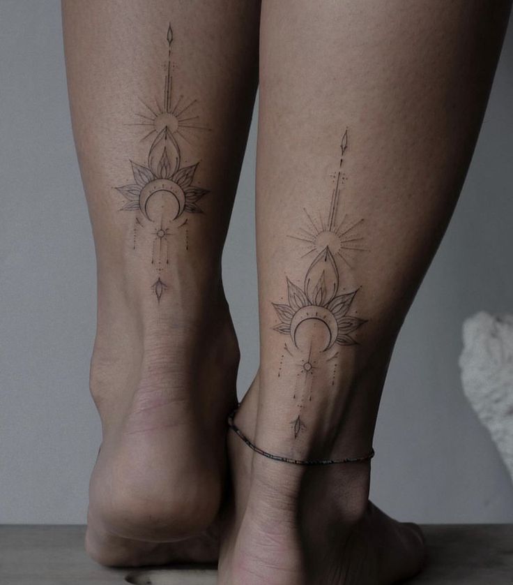 two women's legs with sun and moon tattoos on them