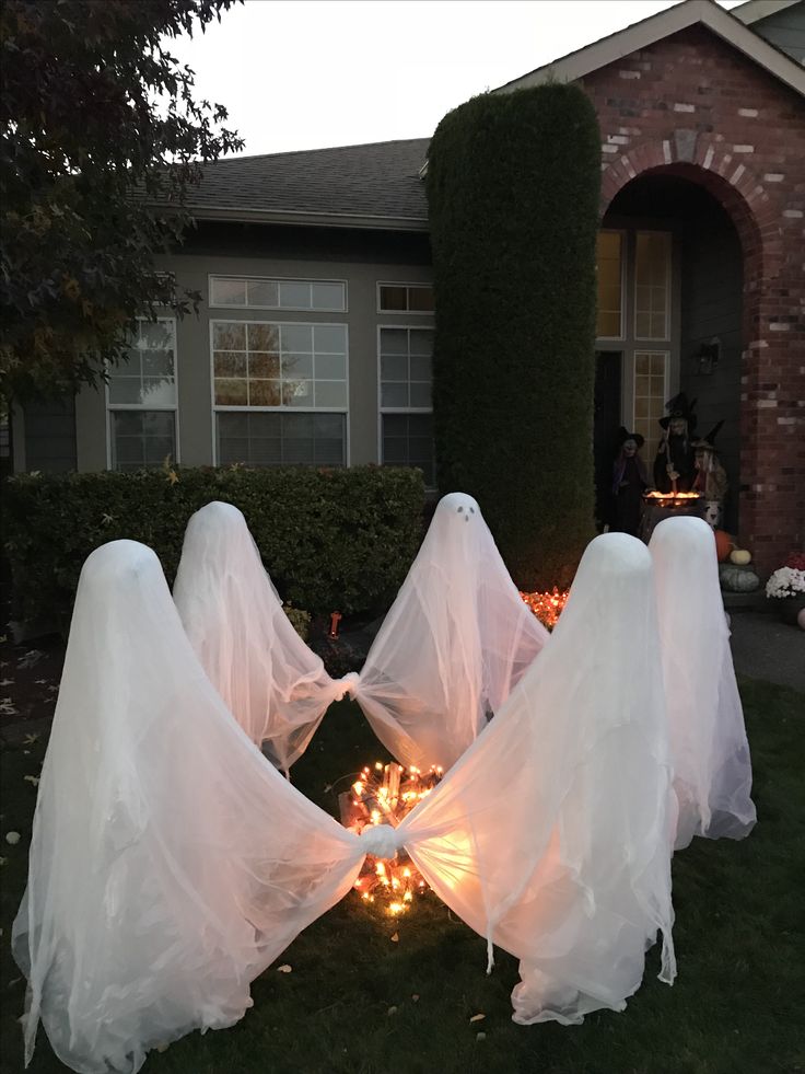 halloween decorations in front of a house with ghost heads on the lawn and lights around them