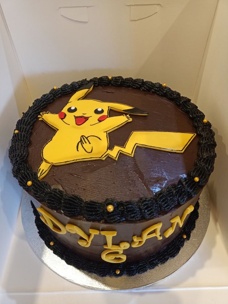 a birthday cake with a pikachu design on the frosting and chocolate icing