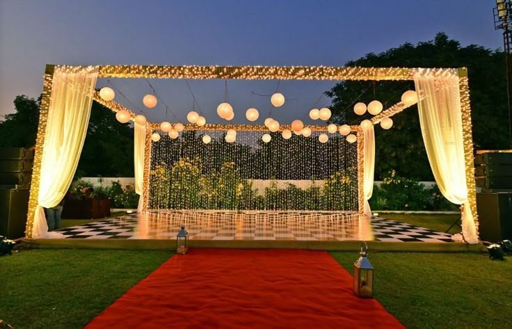 an outdoor wedding setup with white lanterns and red carpet