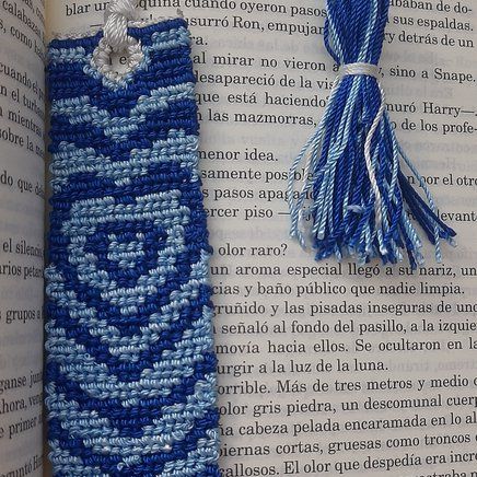 an open book with a tassel on top of it next to a crocheted bookmark