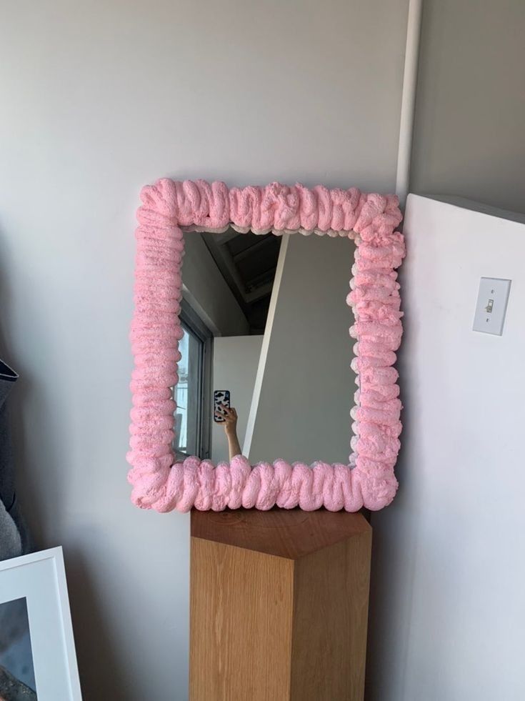 a mirror that is sitting on top of a wooden block in front of a wall