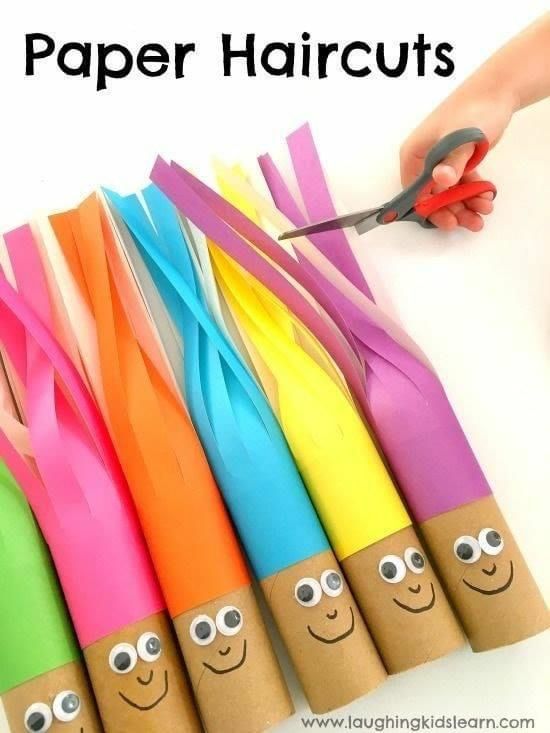 paper haircuts are lined up in different colors and sizes, with one person holding scissors