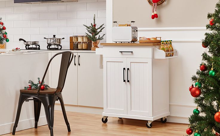 a small kitchen decorated for christmas with red and green ornaments on the walls, white cabinets and black chairs