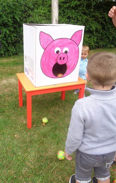 a little boy standing in front of a box with a pig face on it