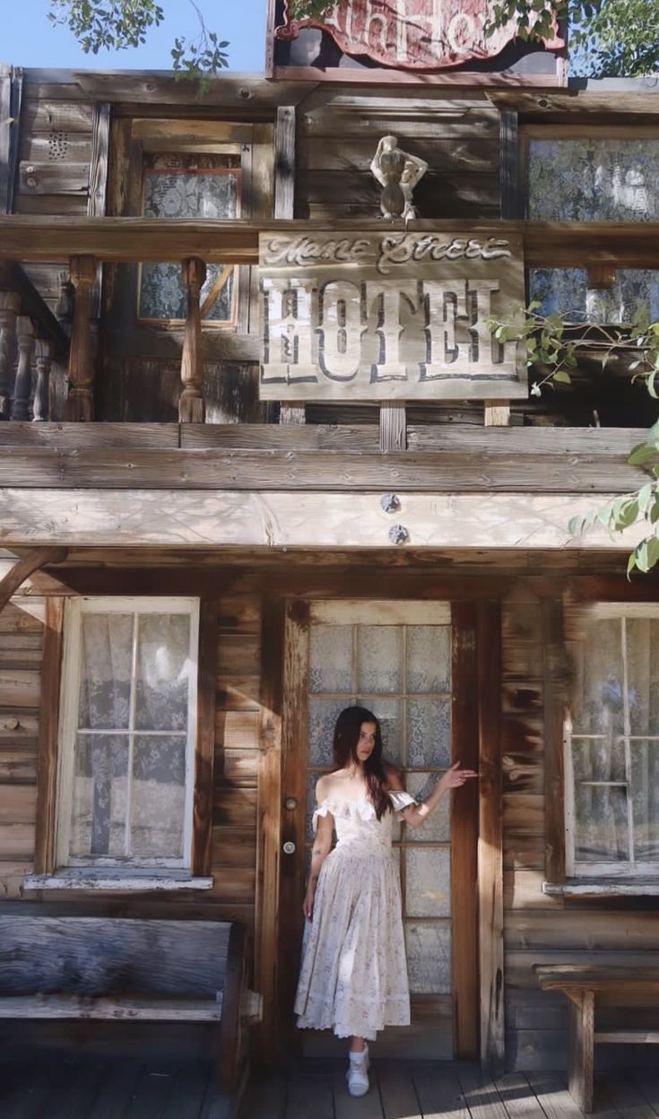 a woman standing in front of a wooden building