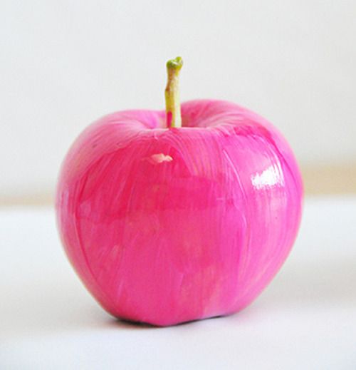 a pink apple sitting on top of a white table