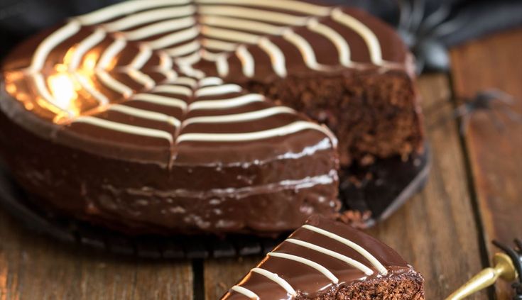 a chocolate cake with white frosting and a spider web design on the top slice