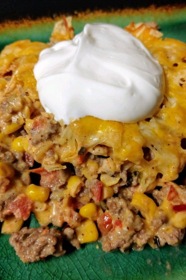 a green plate topped with taco salad and sour cream