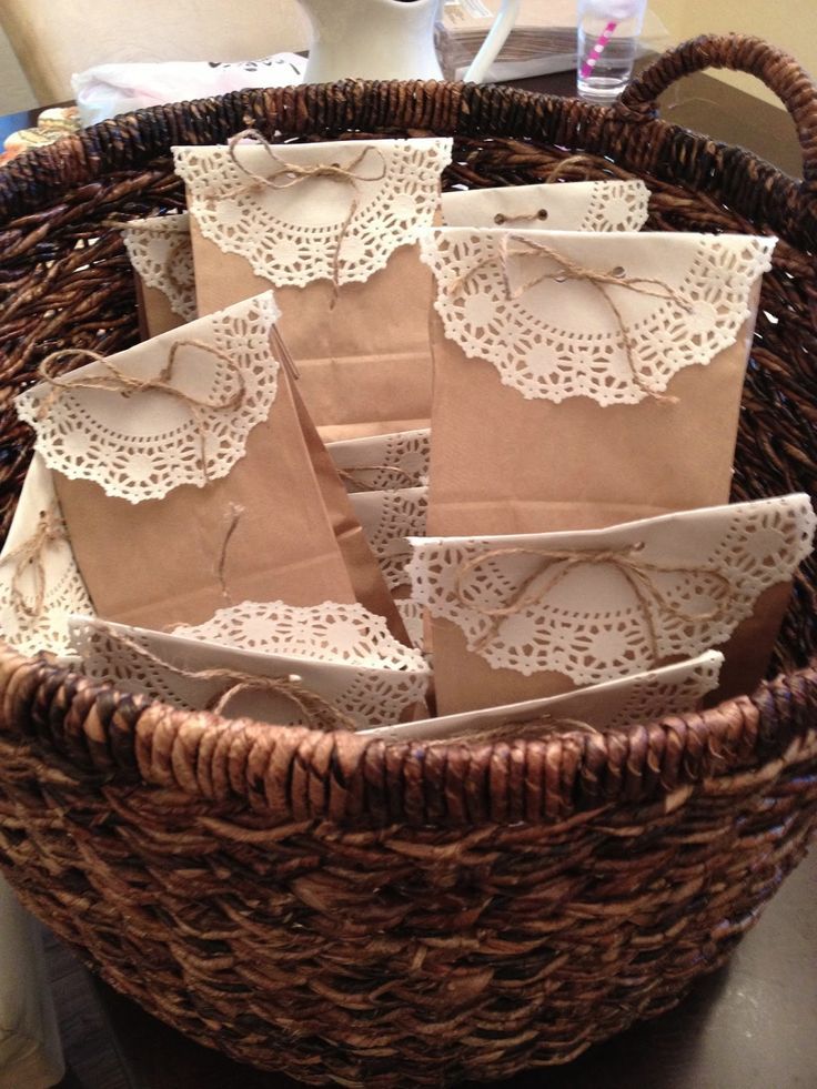 some brown paper bags in a wicker basket on top of a table with white doily