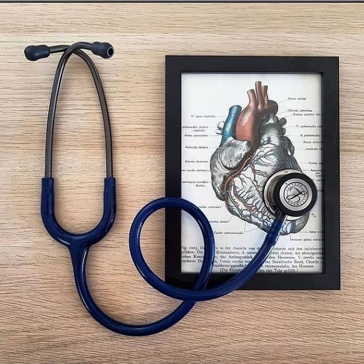 a blue stethoscope sitting on top of a book next to a heart