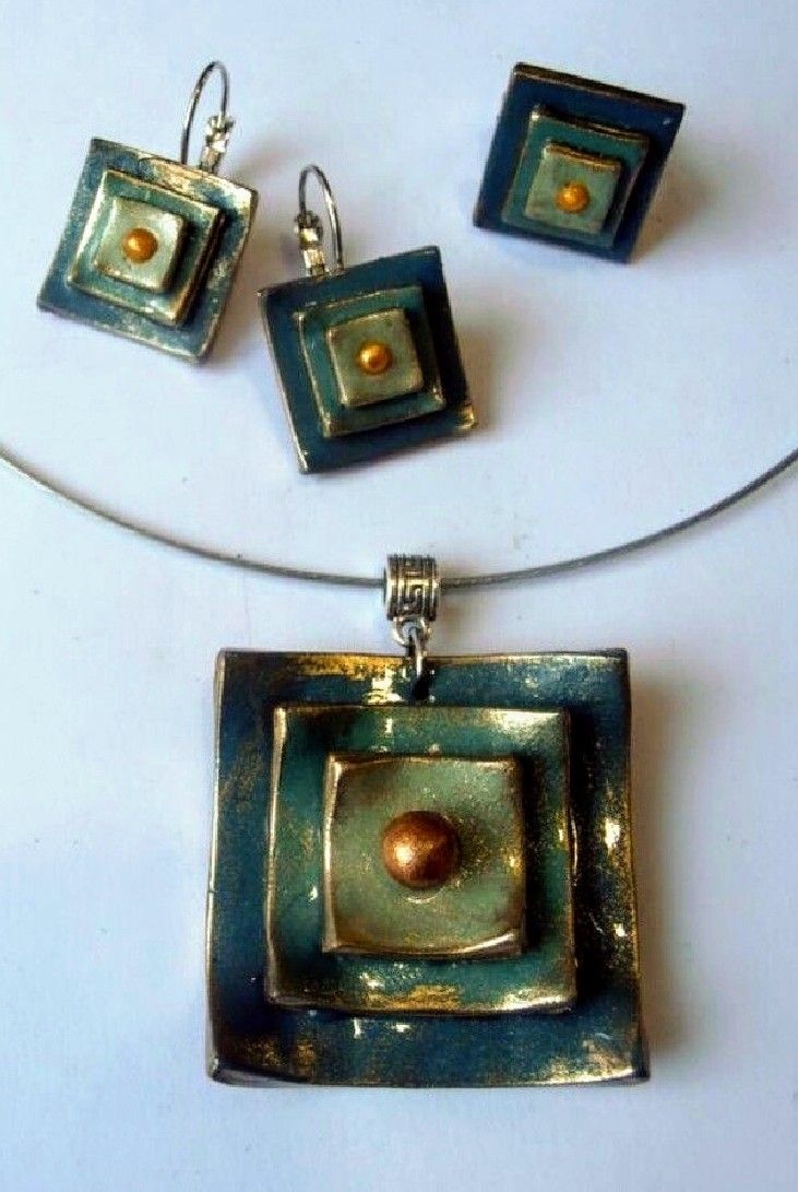 three square pendants and two earrings on a white surface with silver wires attached to them