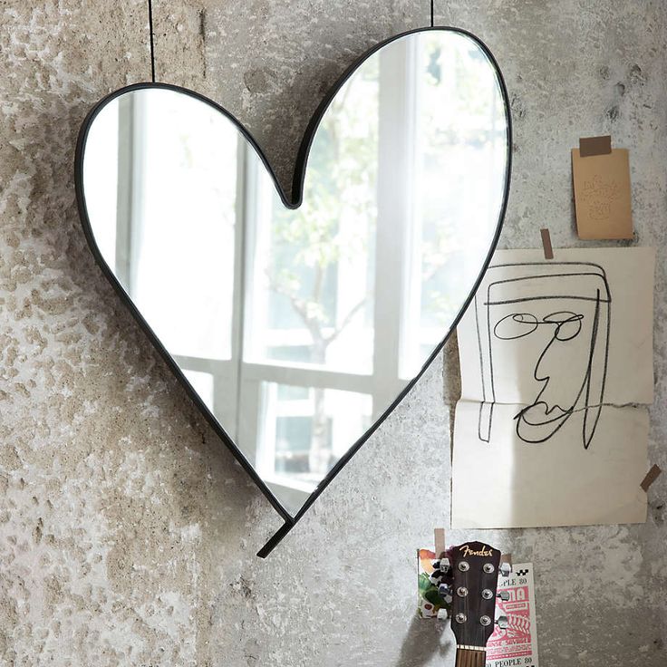 a heart shaped mirror hanging on the side of a wall next to a guitar case