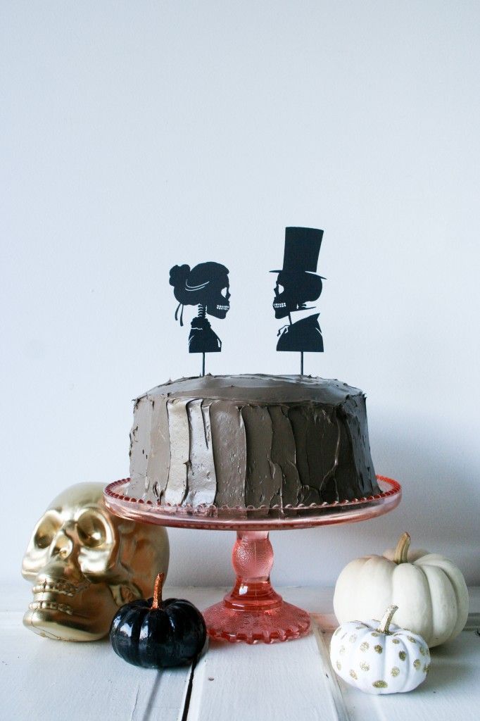 there is a cake on the table with two candles in it and three skulls next to it