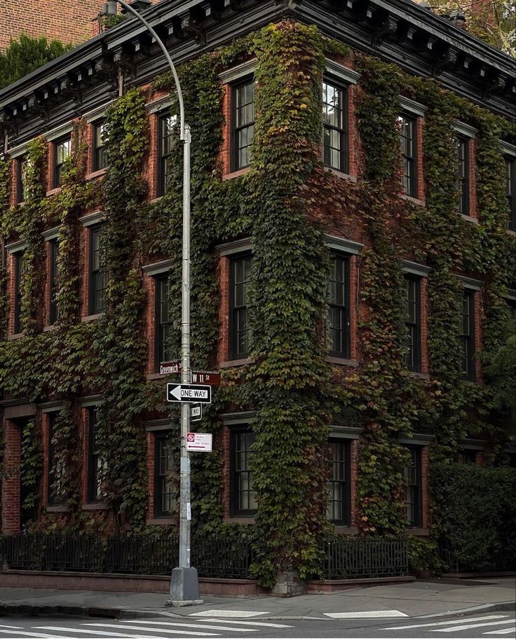 an old brick building covered in vines and ivys on the corner of a street