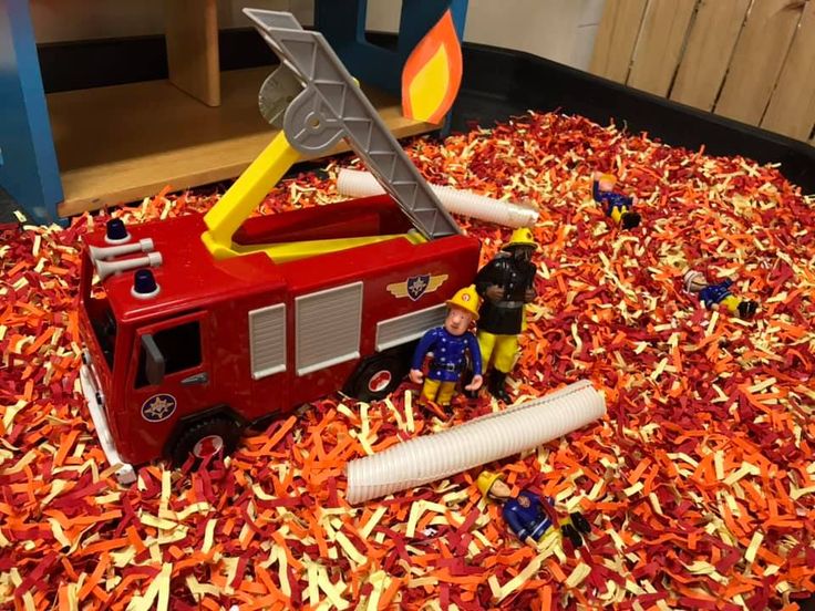 a toy firetruck is surrounded by shredded orange and yellow paper machs on the floor