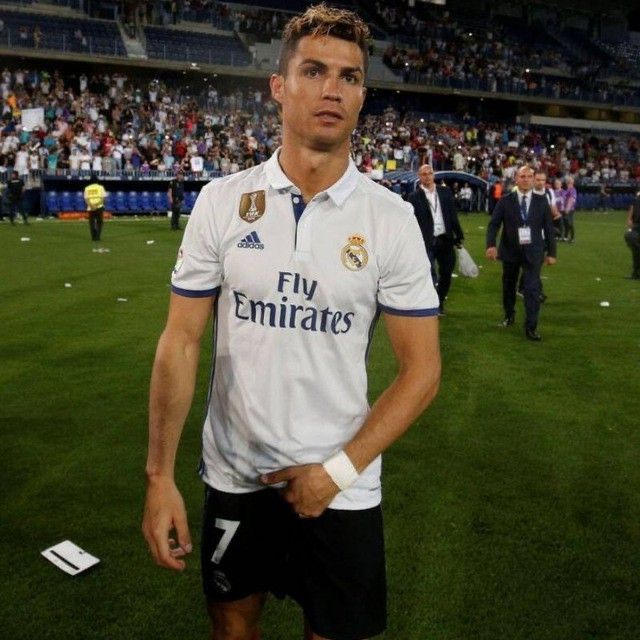 a man standing on top of a soccer field next to a stadium filled with people