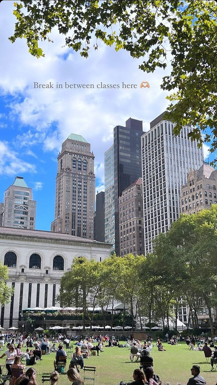 many people are sitting on the grass in front of some tall buildings and skyscrapers