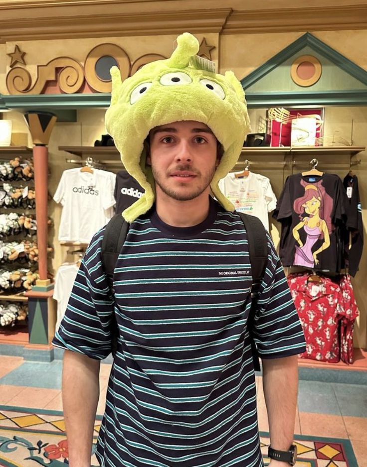 a man wearing a green frog hat in a store