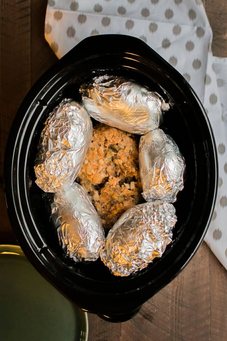 some food is in a black bowl on a wooden table next to a white and gray napkin