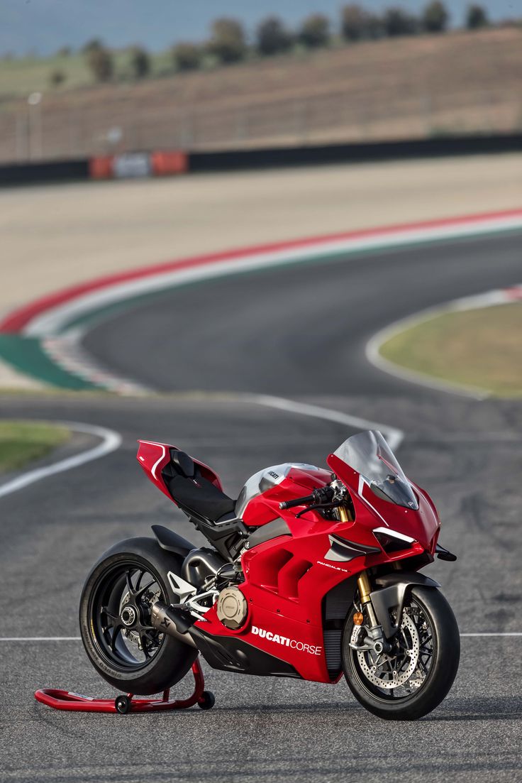 a red motorcycle parked on the side of a race track