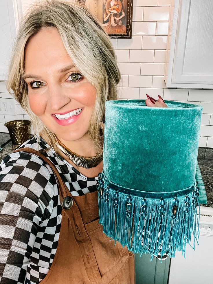 a woman holding up a green cake with blue fringes on the top and bottom