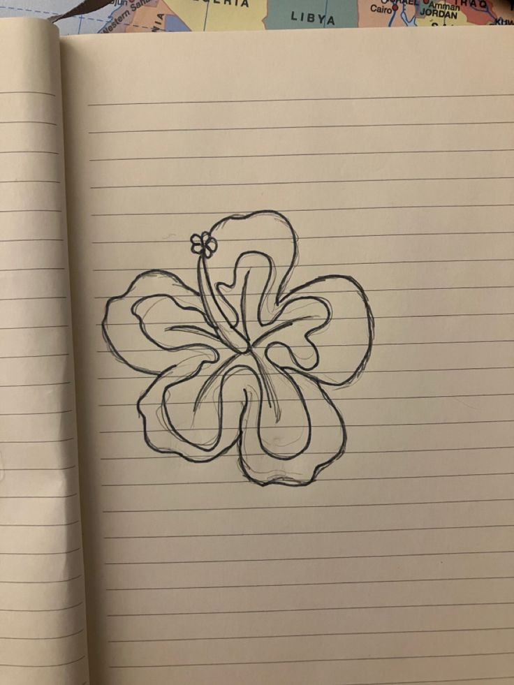 an open notebook with a drawing of a flower on the page next to a map