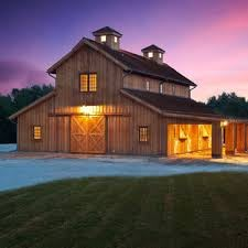 a barn lit up at night with lights on the front and side doors open to let in light