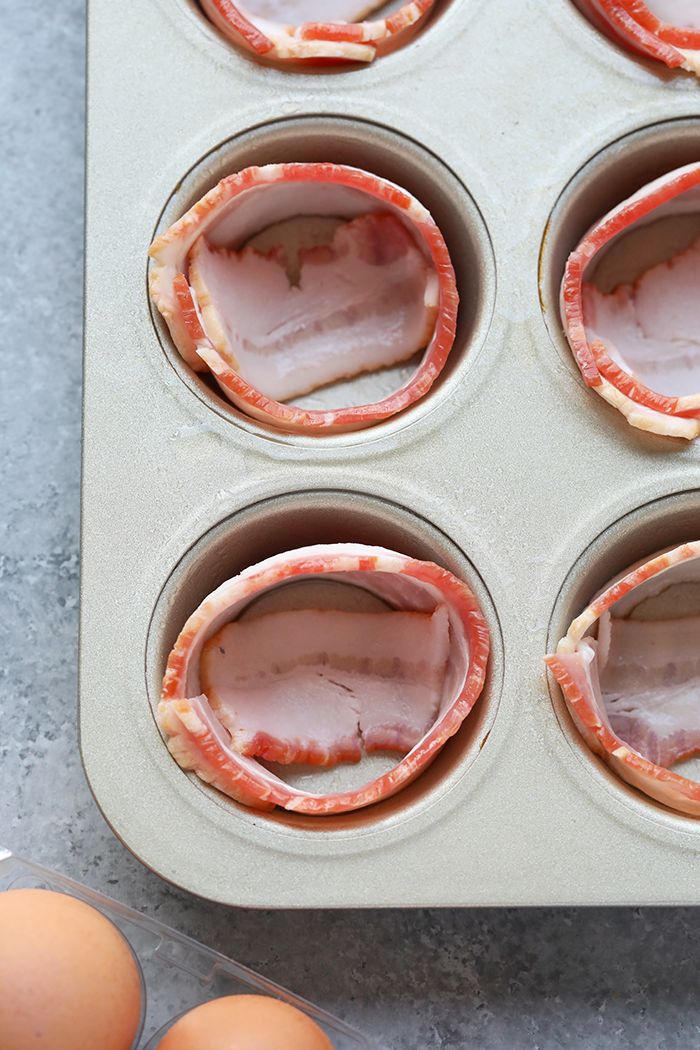 several muffin tins filled with meat and eggs on top of a gray counter