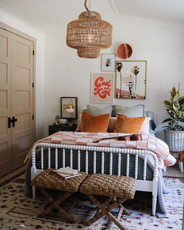 a white bed sitting in a bedroom next to a wooden table and two stools