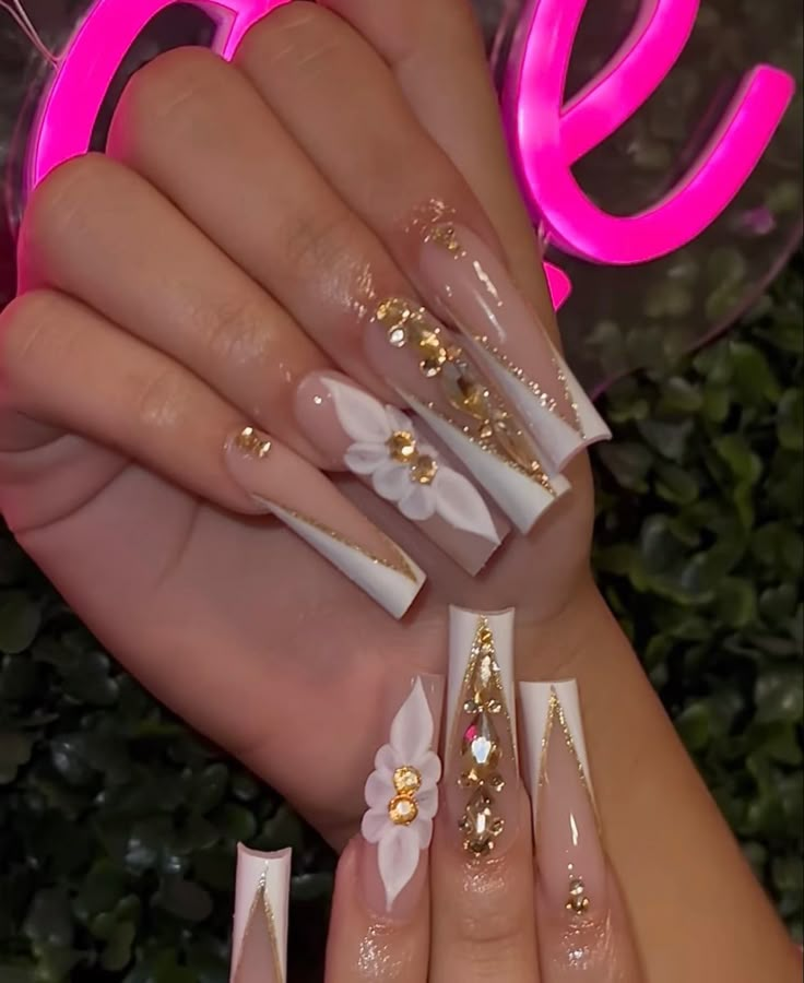 White And Gold Long Nails, White And Gold Acrylic Nails With Design, White French Tip With Gold Charms, White And Gold Quince Nails, White Mexican Nails, White Nails With Gold Rhinestones, White N Gold Nails, Gold Nails With Flowers, White And Gold Birthday Nails