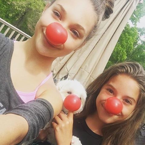 two girls with clown noses and one holding a dog