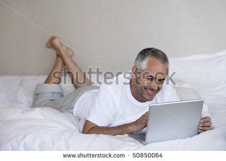 a man laying in bed using a laptop computer