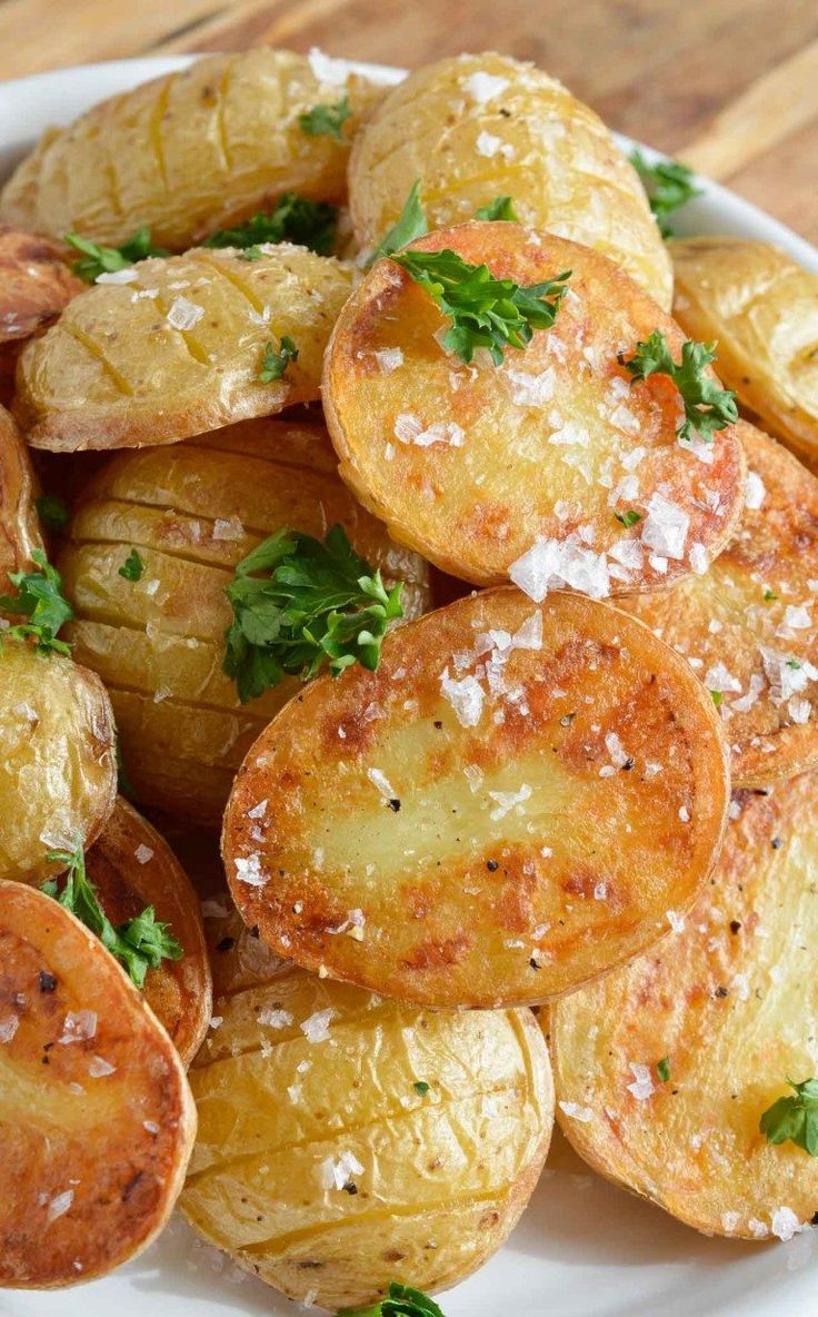 potatoes with parmesan cheese and herbs in a white bowl on a wooden table