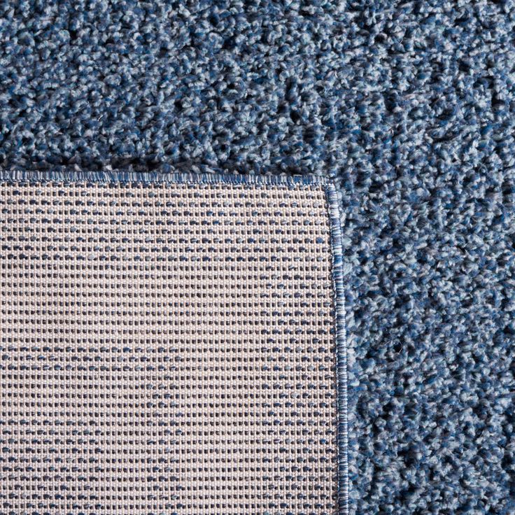 closeup of blue carpet with small squares on the top and bottom corner, viewed from above