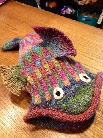 a knitted fish hat sitting on top of a wooden table