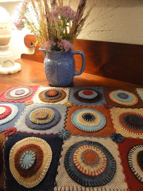 a blue vase with flowers on top of a table next to a rug and lamp