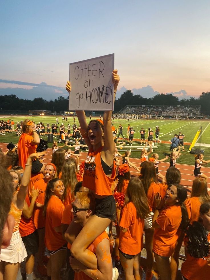 a group of people standing on top of a football field holding up a sign that reads, there is no home