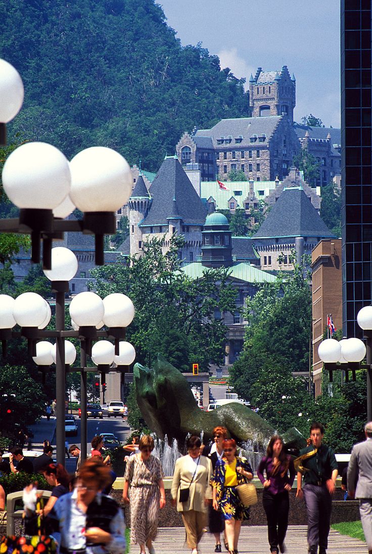 many people are walking on the sidewalk near some buildings