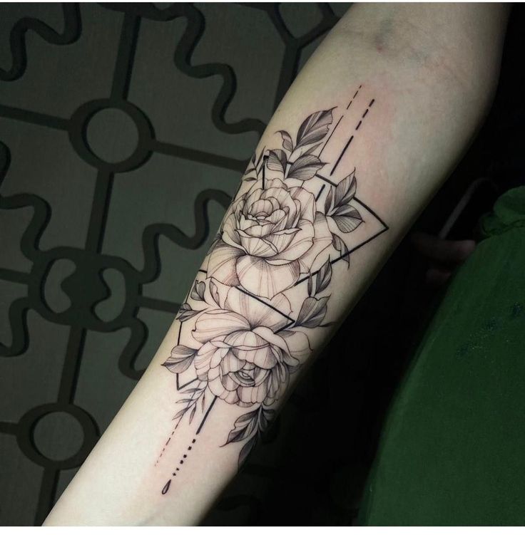 a woman's arm with flowers on it and an arrow in the middle,