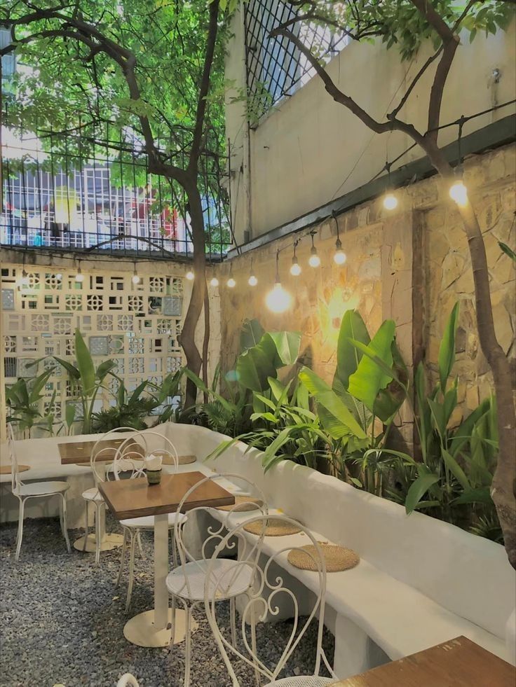 tables and chairs are lined up against the wall with plants growing on them in an outdoor cafe