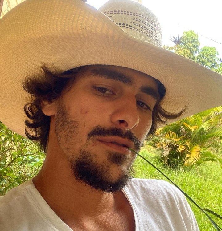 a man wearing a white cowboy hat with long hair