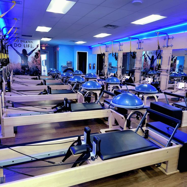 an empty gym with rows of exercise machines and blue lights on the ceiling in front of them