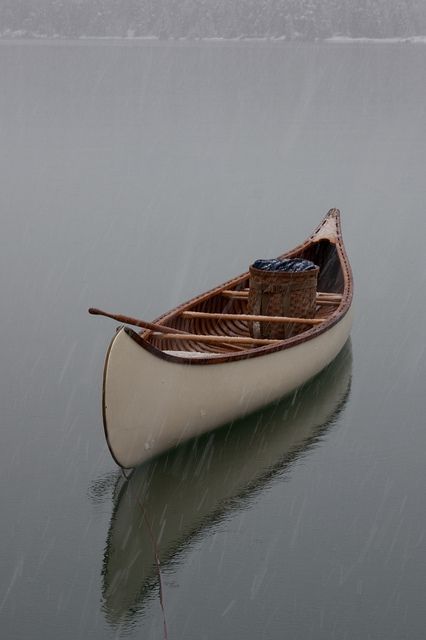 a small boat floating on top of a lake in the rain with no one inside