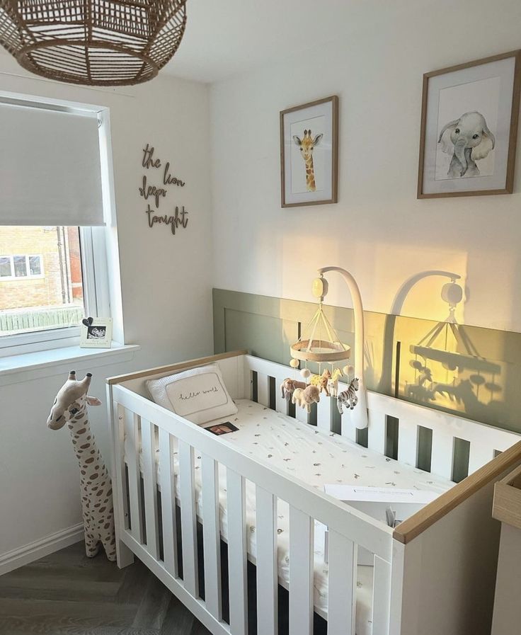 a baby crib in the corner of a room with pictures hanging on the wall